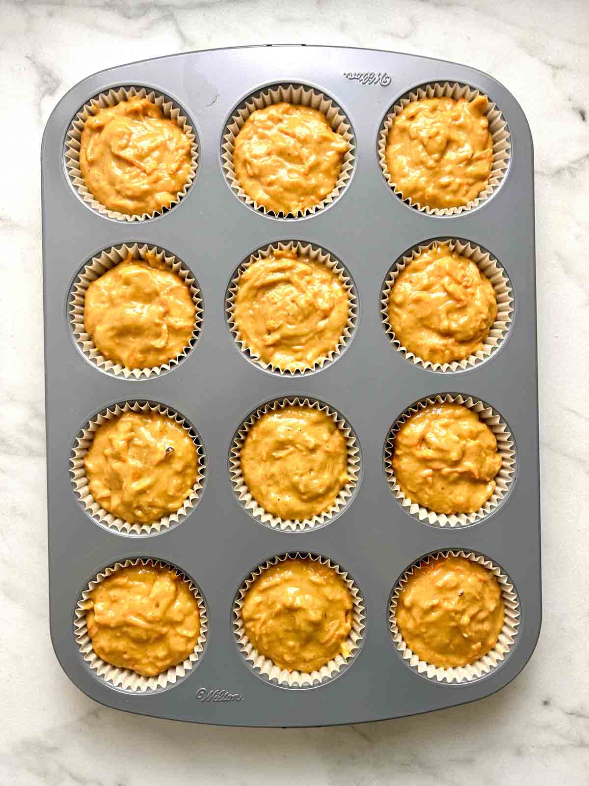 batter spooned into muffin liners in muffin pan.