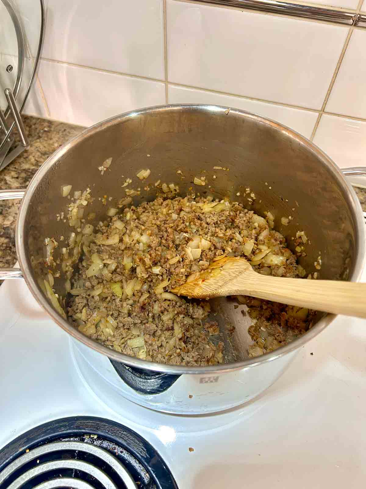 Italian sausages, onions, and garlic sautรฉed in pot.
