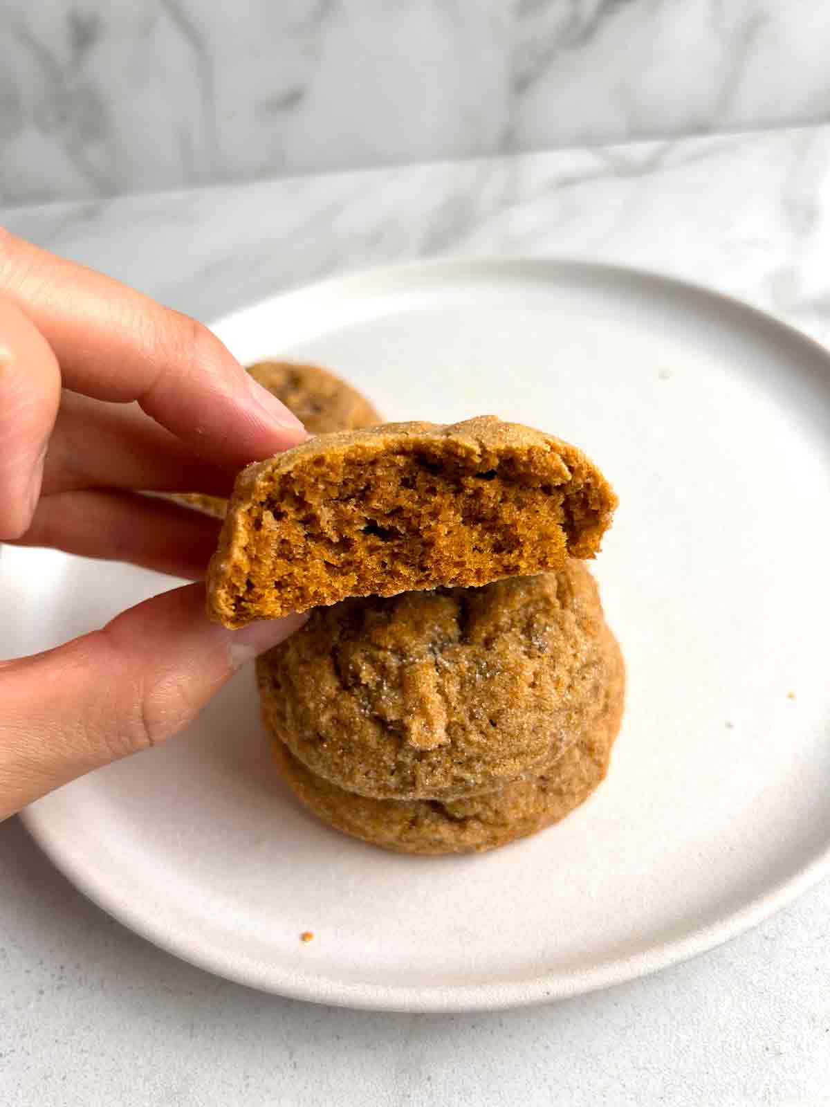 hand holding half of pumpkin cookie.