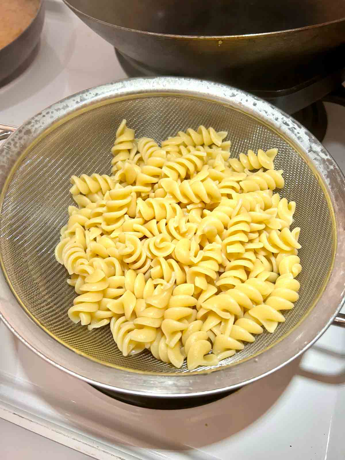 rotini pasta draining over pot.