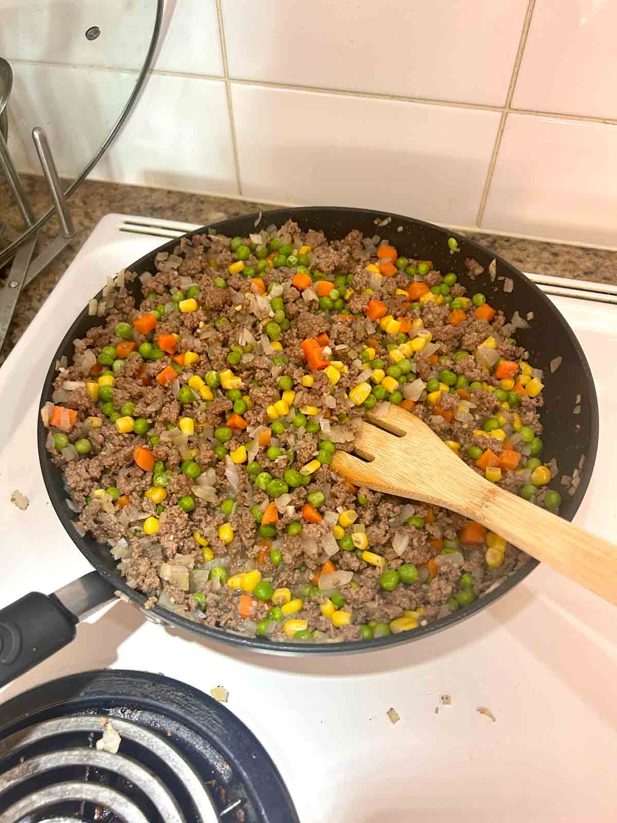 add mixed vegetables to ground beef, garlic, and onion.