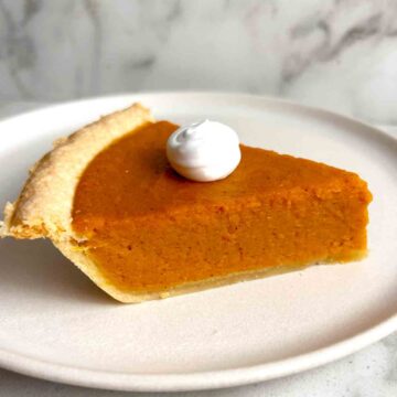 slice of sweet potato pie with cream on top.