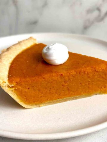 slice of sweet potato pie with cream on top.