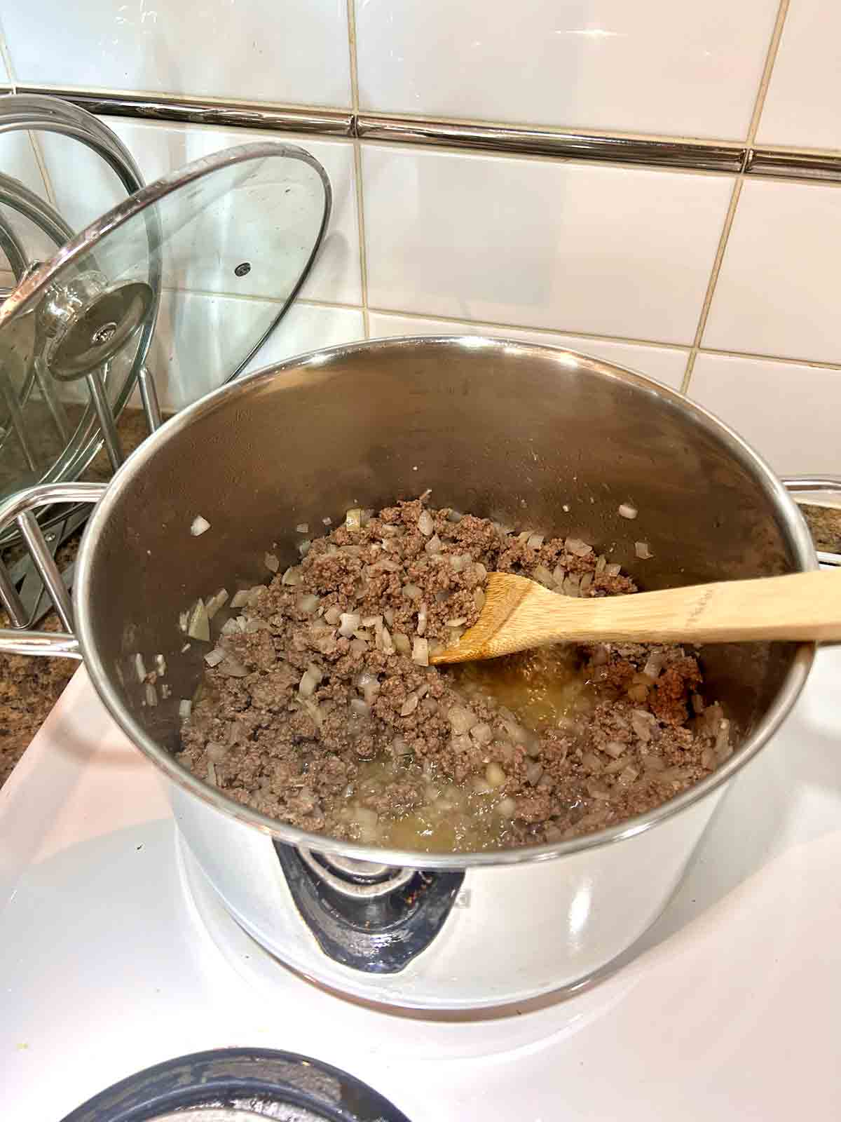 ground beef, garlic, and onion being cooked in pot.