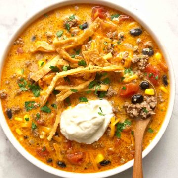bowl of taco soup with sour cream, cilantro, and cheese added on top.