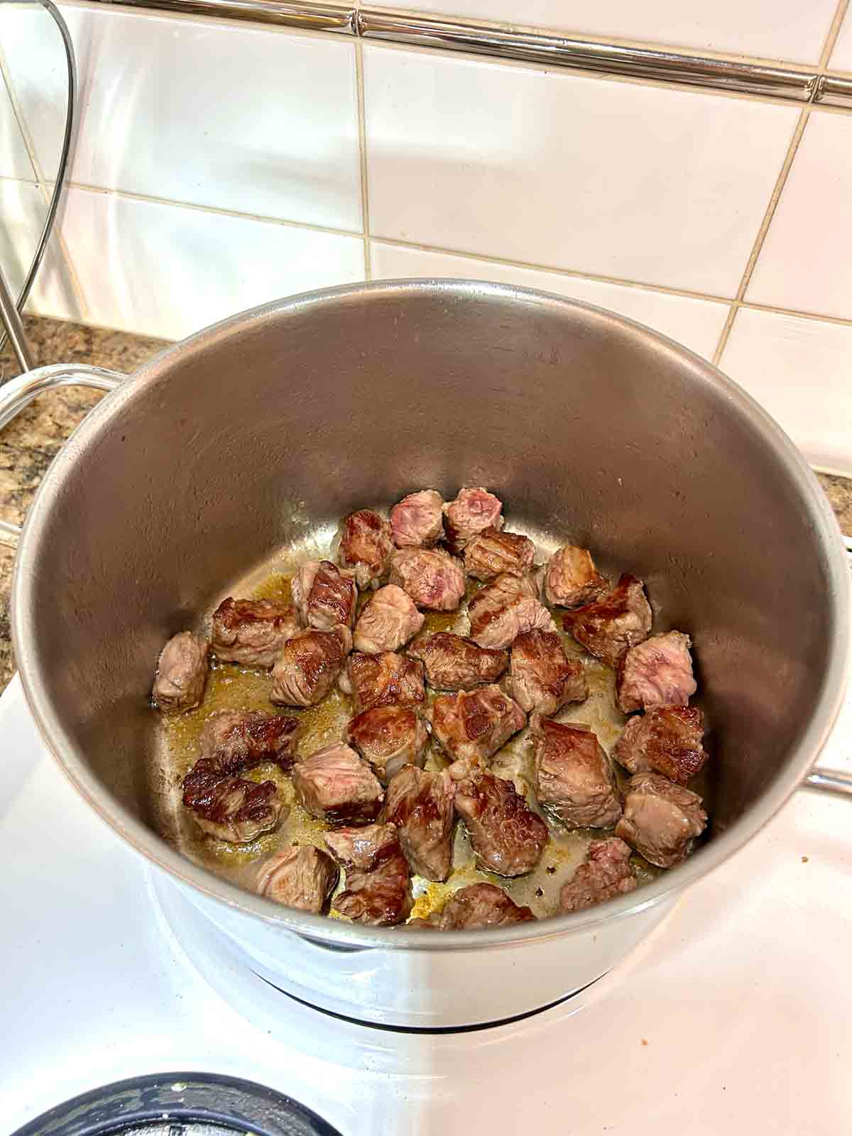 beef chunks being seared in pot.
