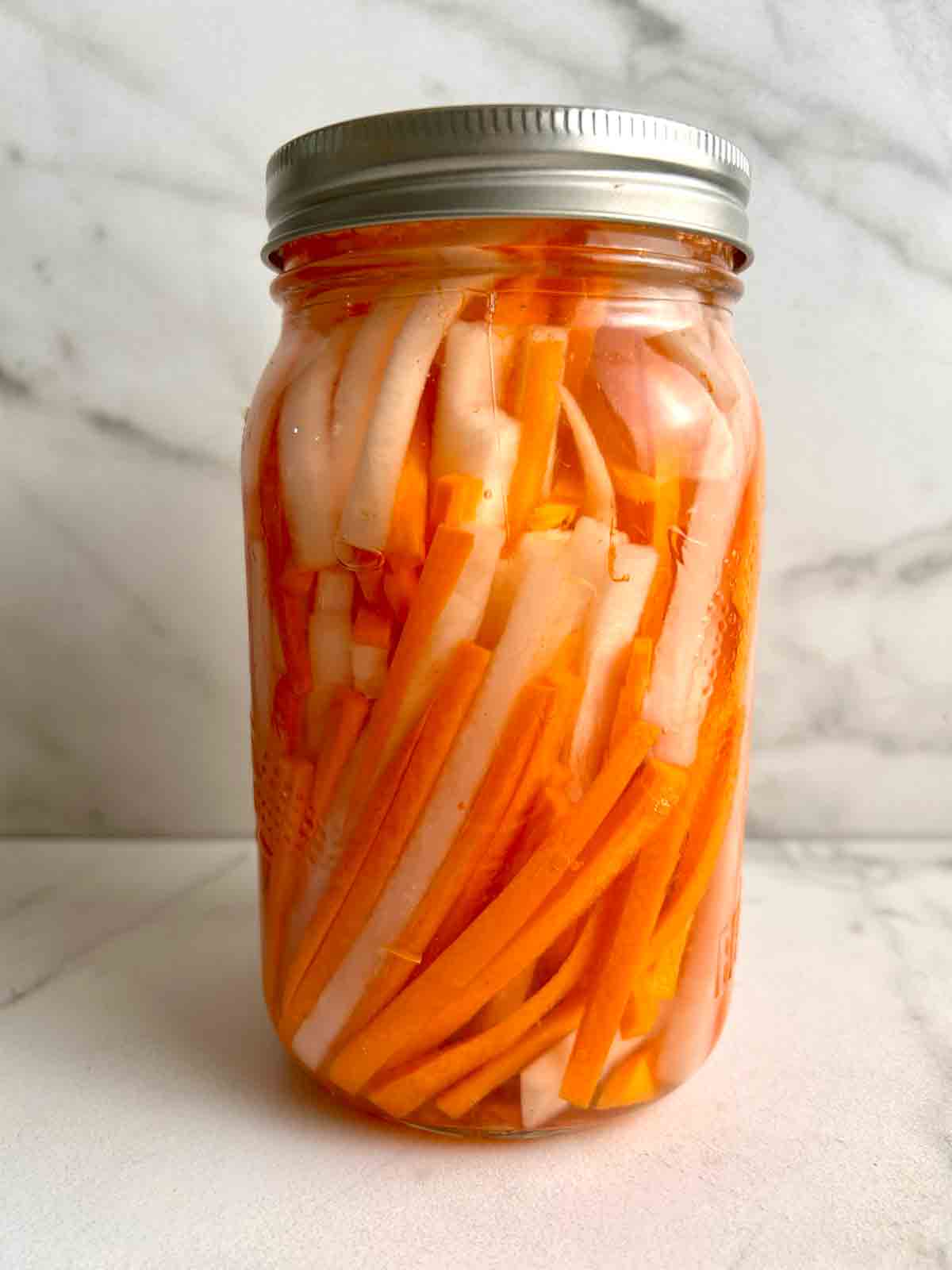 jar of pickled daikon and carrots with brine.