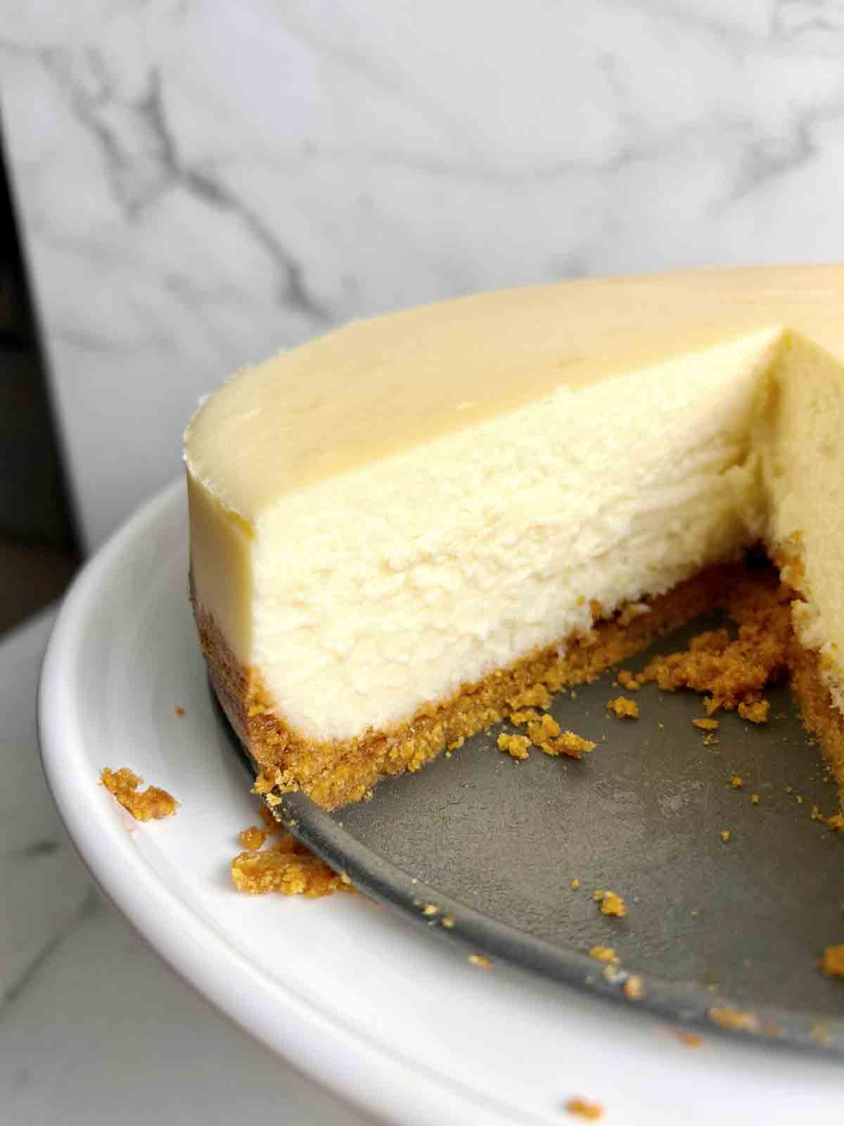 cheesecake on cake stand with slice taken out of it.