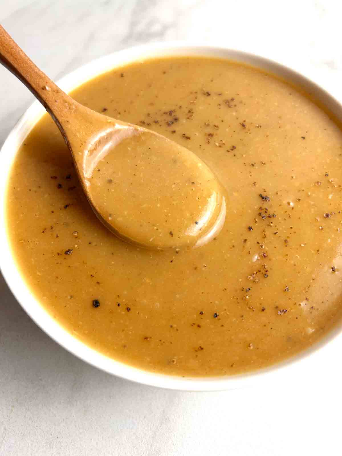 spoon lifting gravy from bowl.