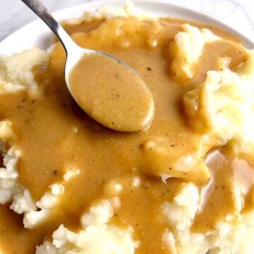 spoon lifting gravy onto mashed potatoes.