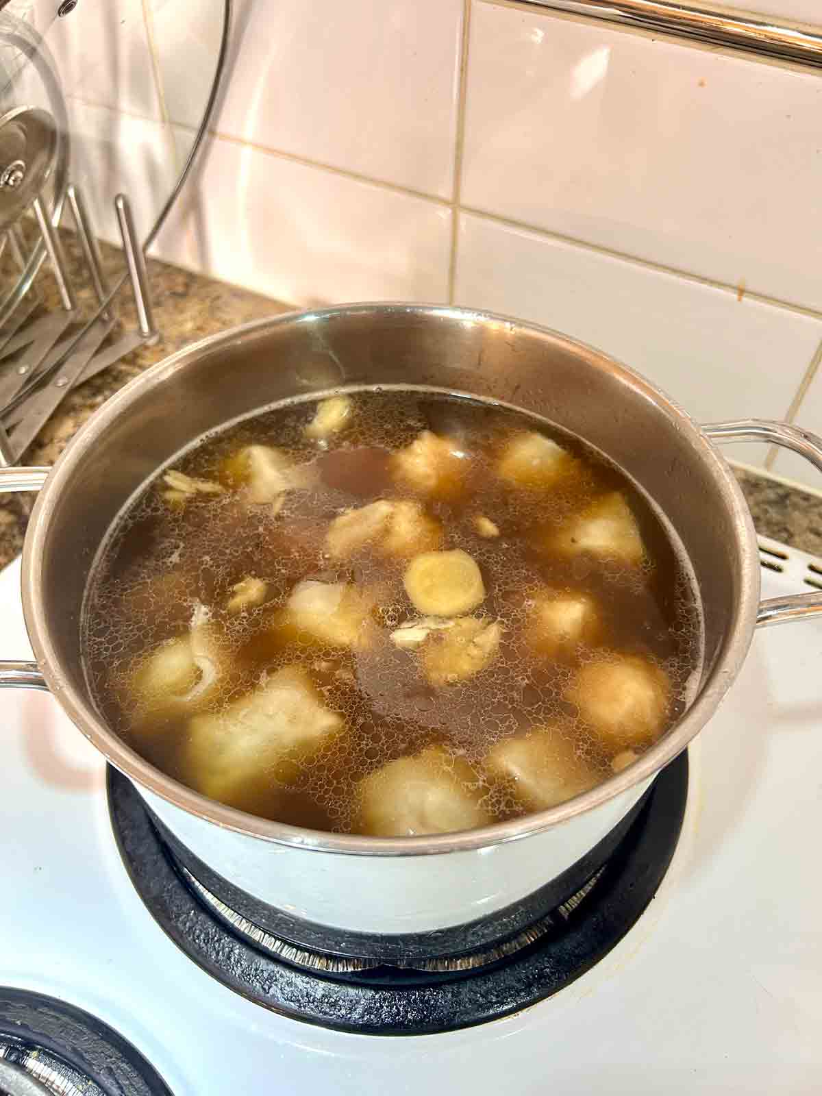wontons simmering in pot of soup.