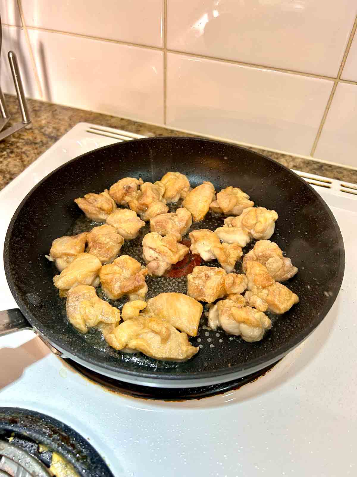 chicken pieces fried in pan.