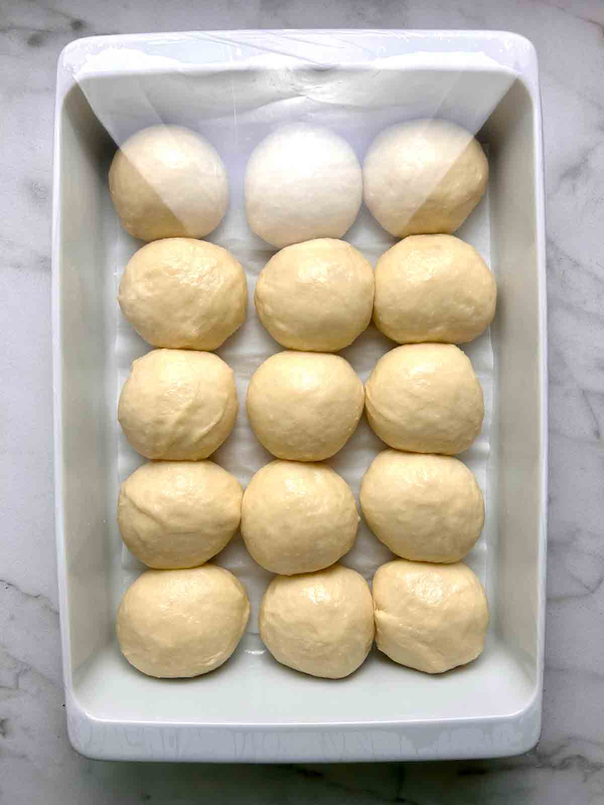 dough shaped into balls in 9 by 13 baking dish.