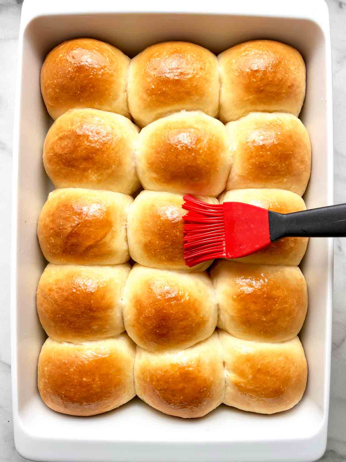 brushing butter onto baked rolls.