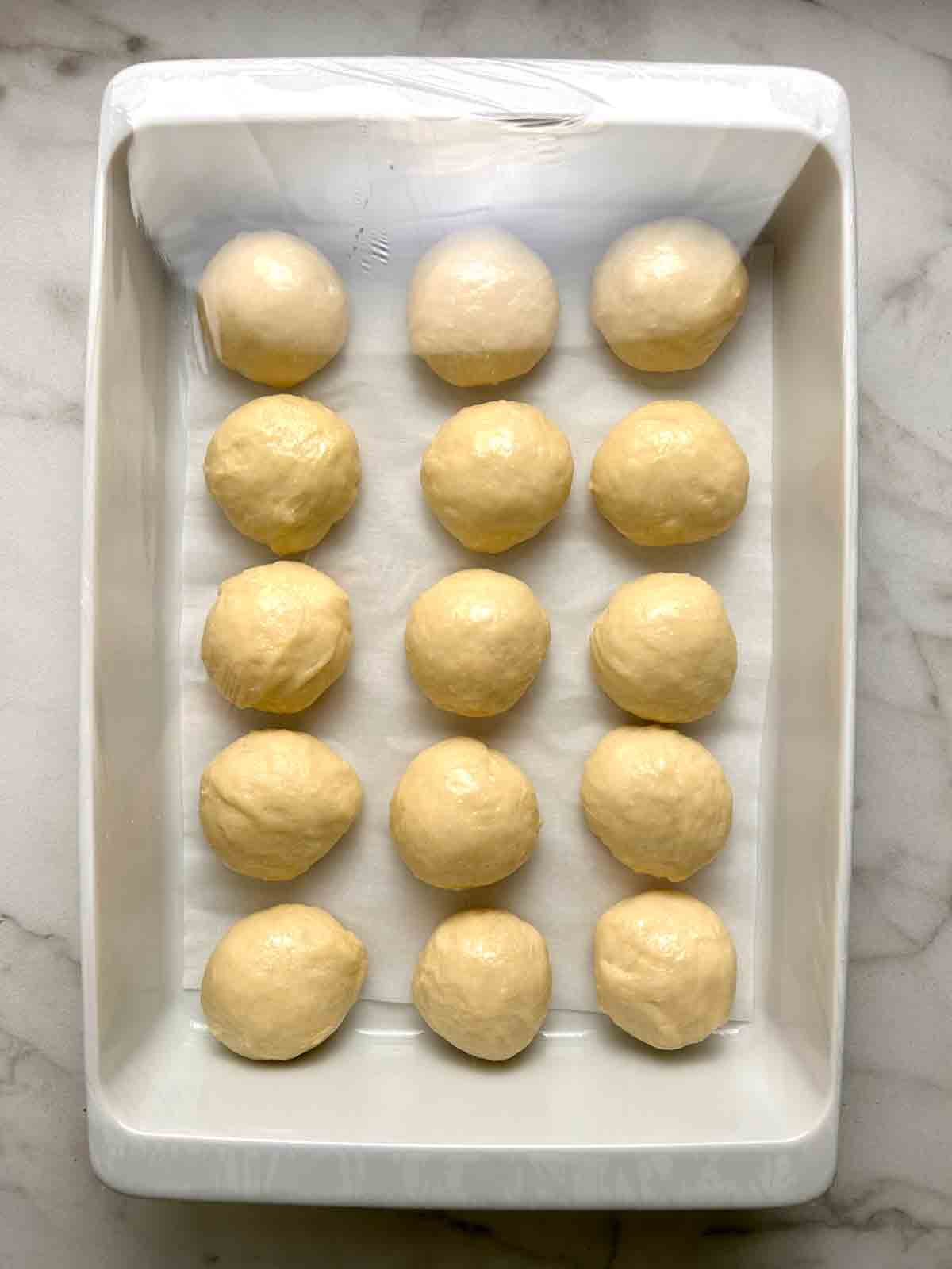dough shaped into balls in 9 by 13 baking dish.