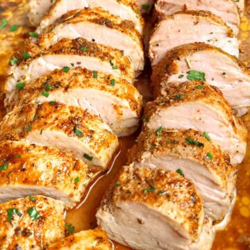 baked pork tenderloin sliced and garnished with chopped parsley.