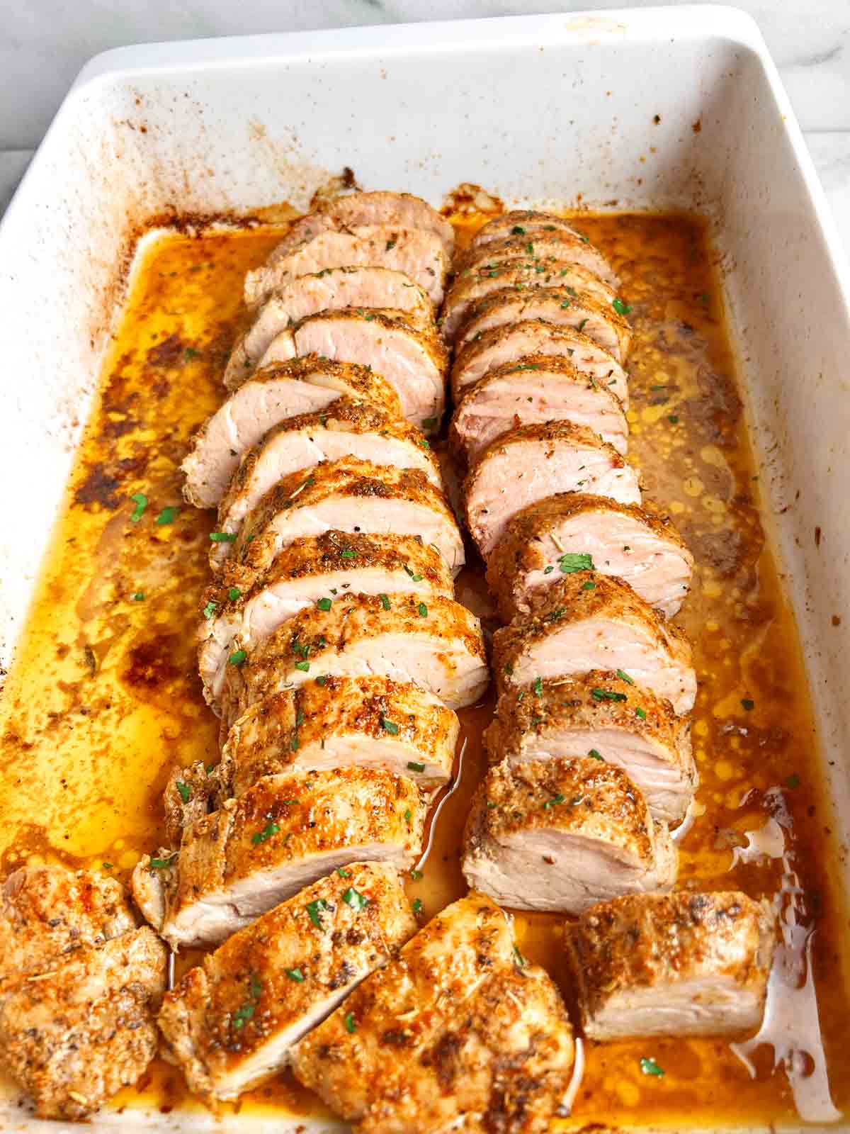 baked pork tenderloin sliced and garnished with chopped parsley.