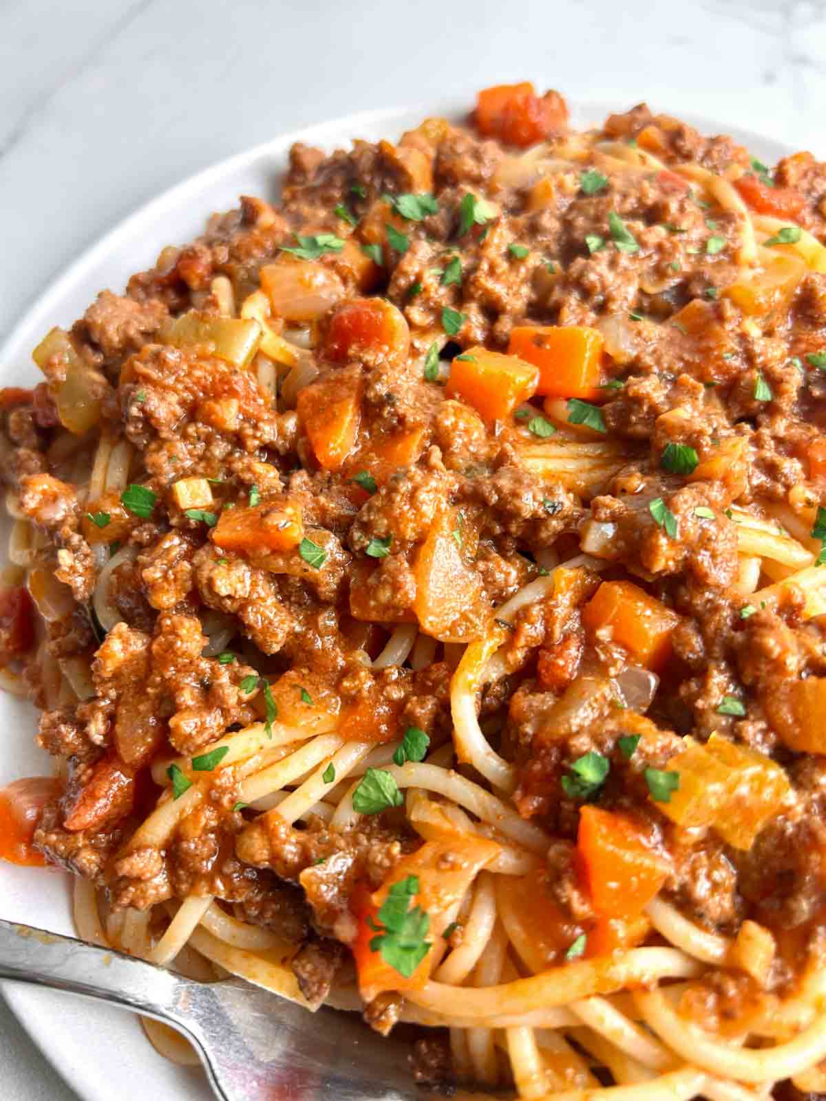 close up of bolognese sauce over spaghetti.