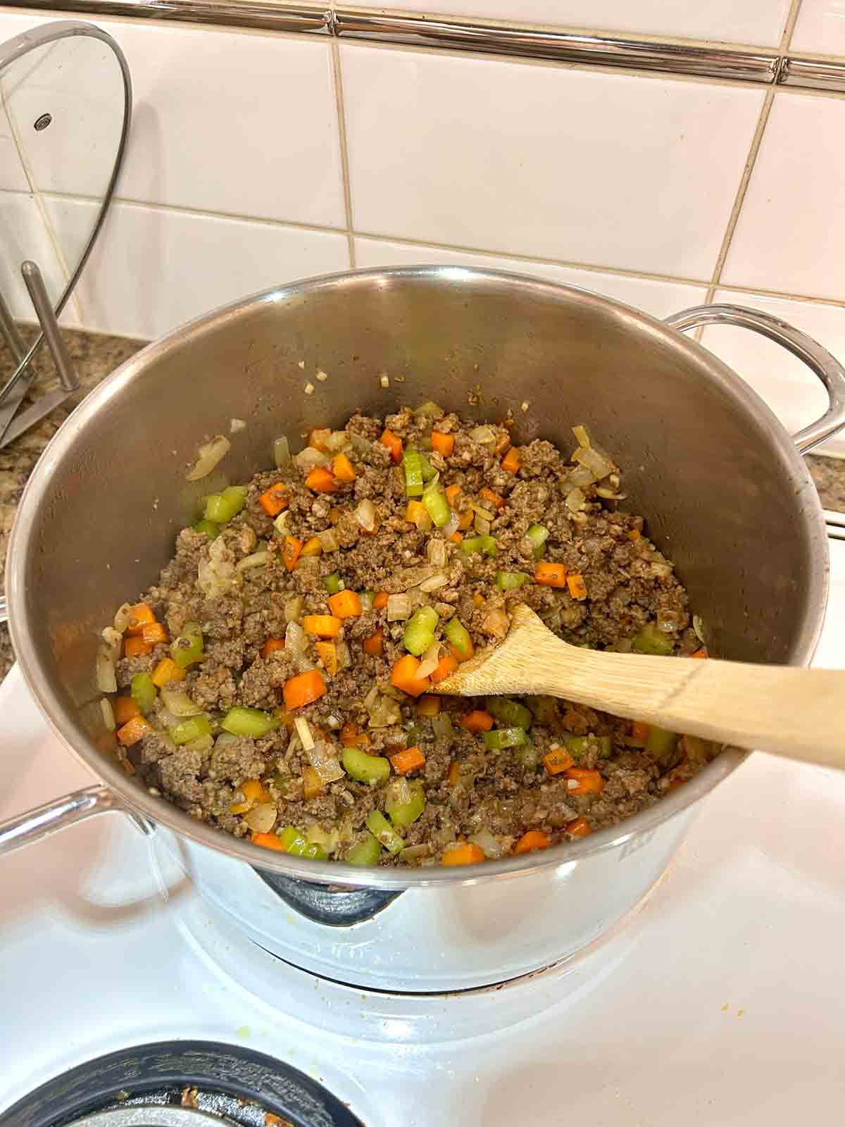 vegetables and meat being sautรฉed in pot.