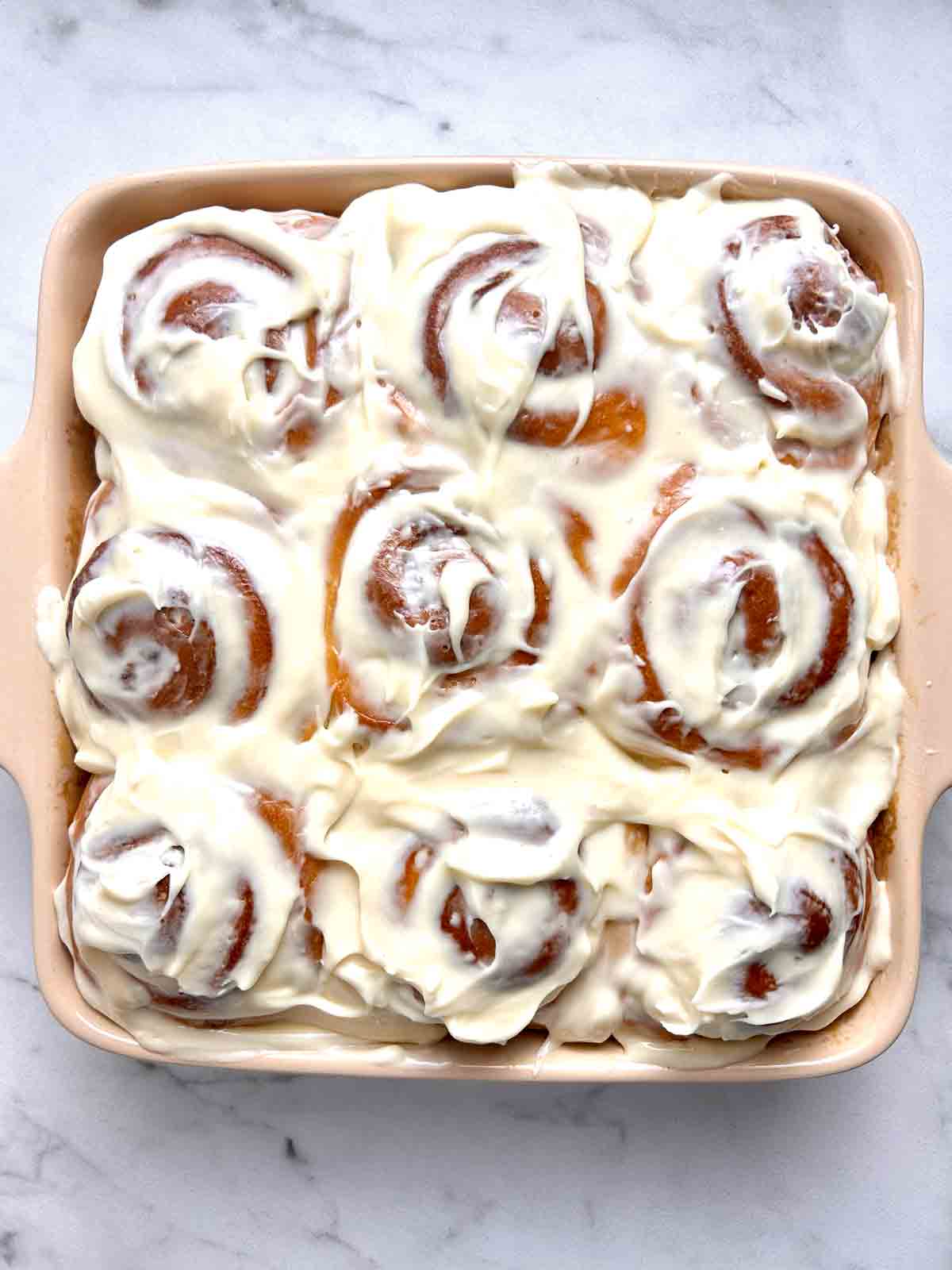 frosting spread on top of cinnamon rolls.