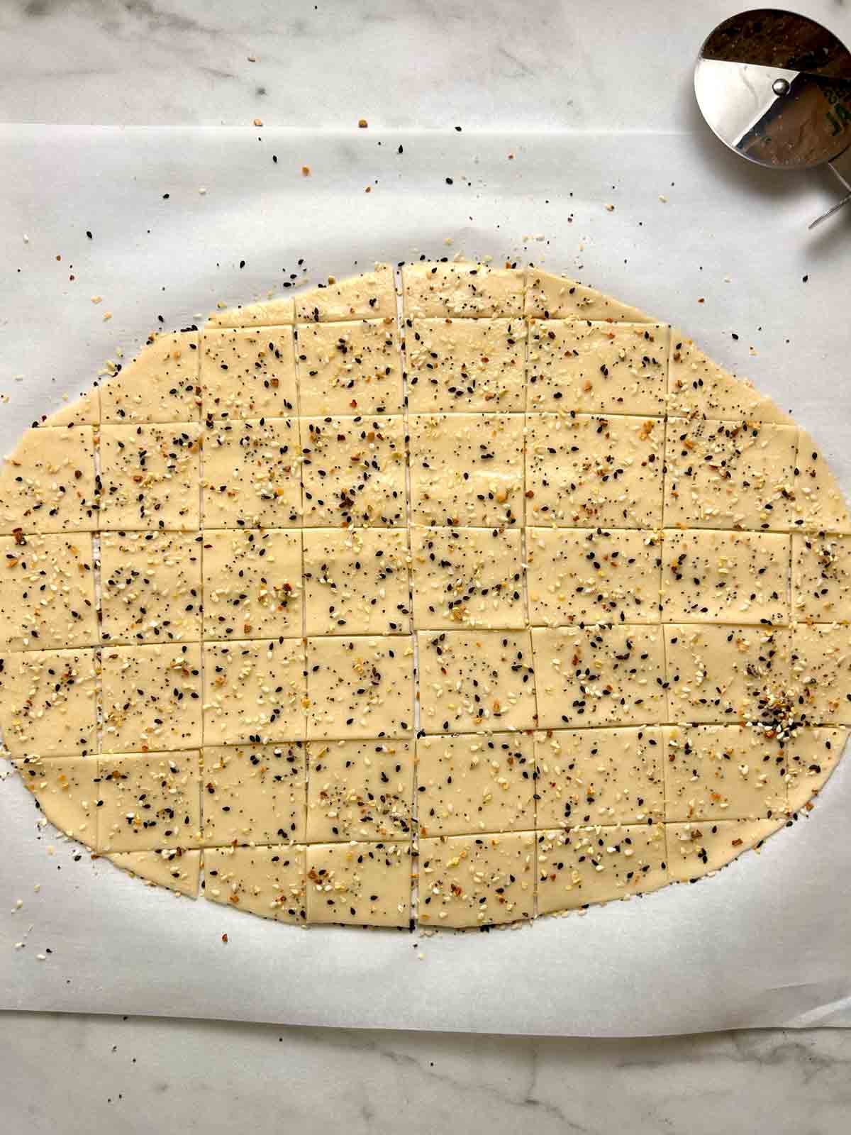 dough cut into squares with everything bagel seasoning sprinkled all over.