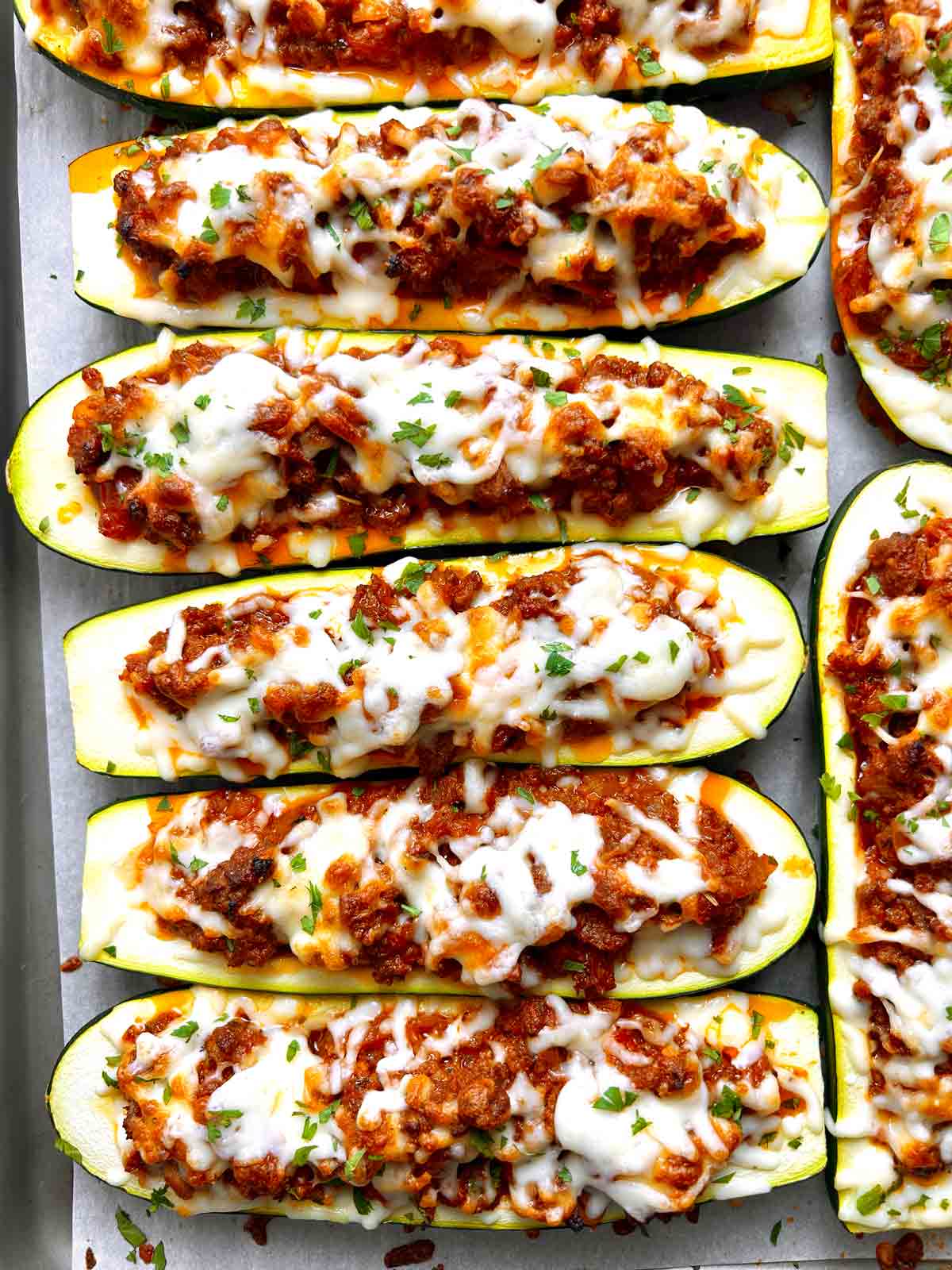 close up of stuffed zucchini boats on baking sheet.