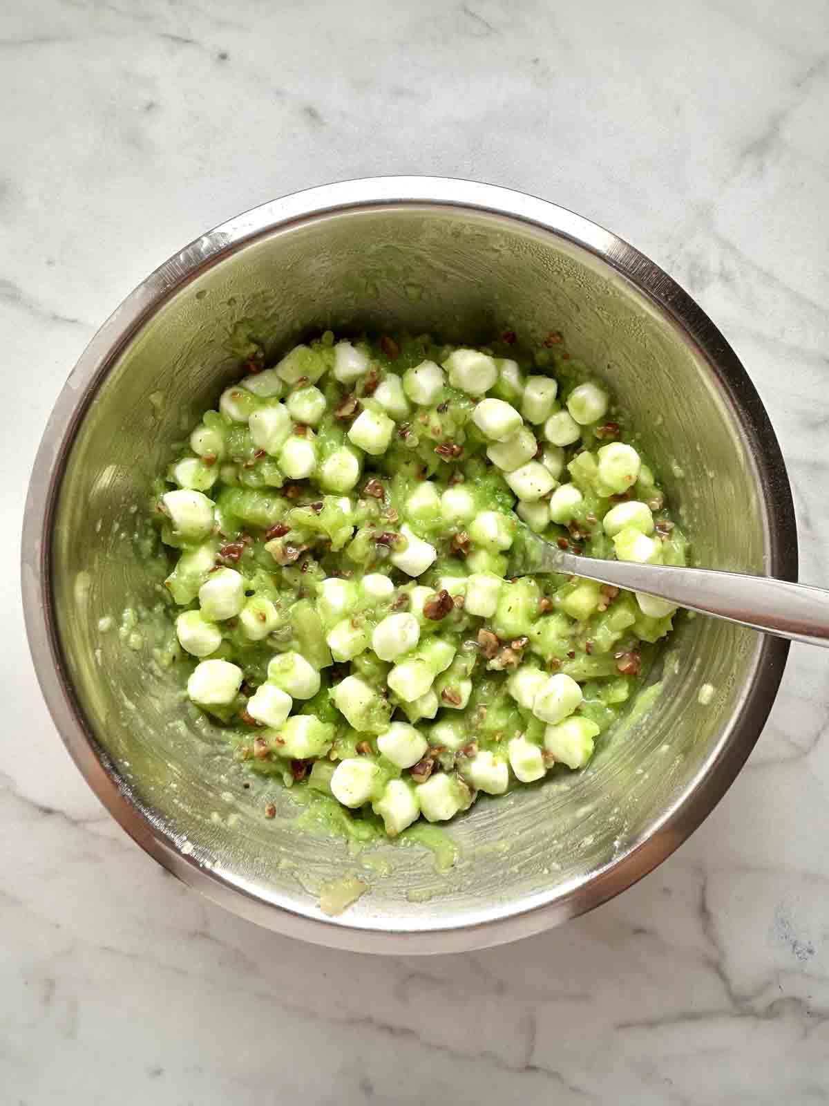 pineapples, marshmallows, pecans, and pudding mix combined in bowl.