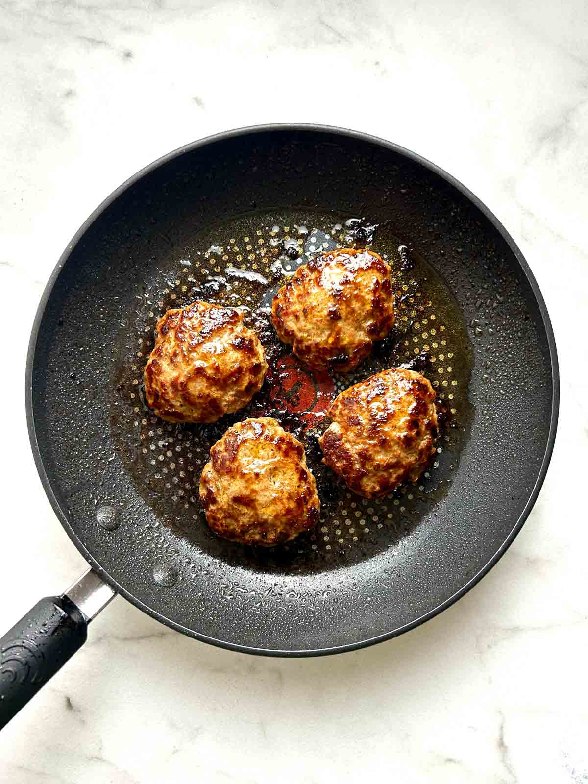 cooked sausage patties in pan.