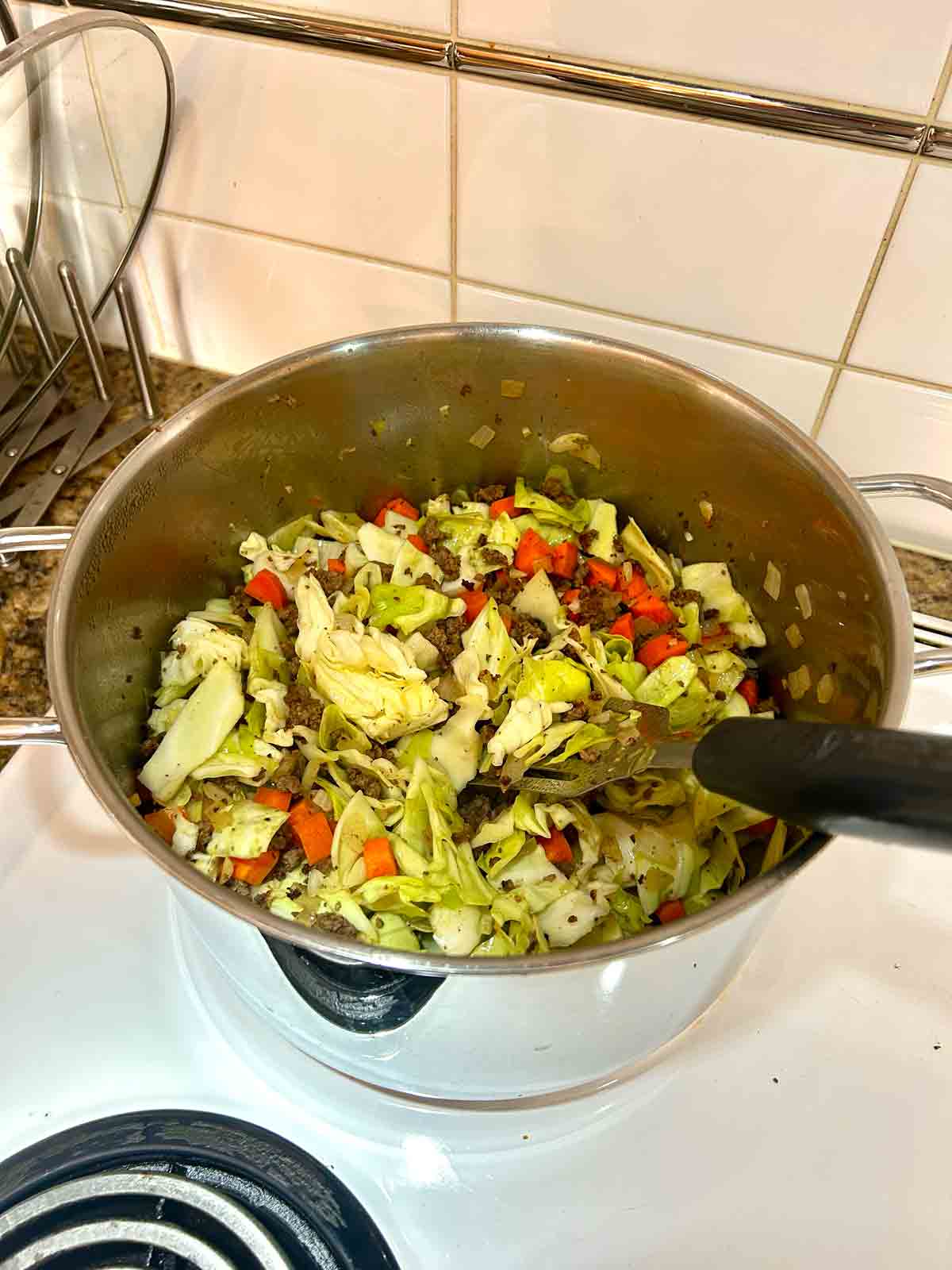 cabbage and carrots sautรฉed with beef mixture in pot.