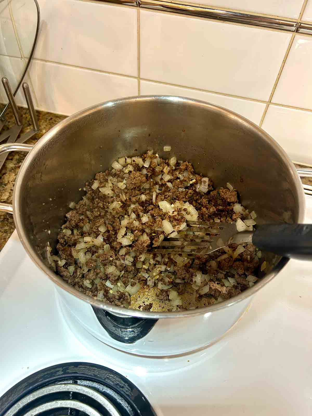 ground beef, onions, and garlic sautรฉed in pot.