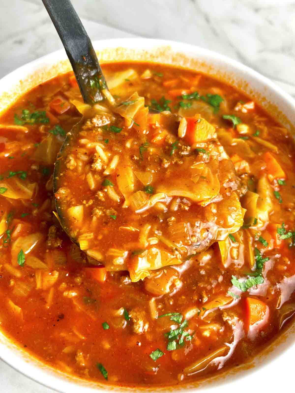 cabbage roll soup being ladled out of big bowl.