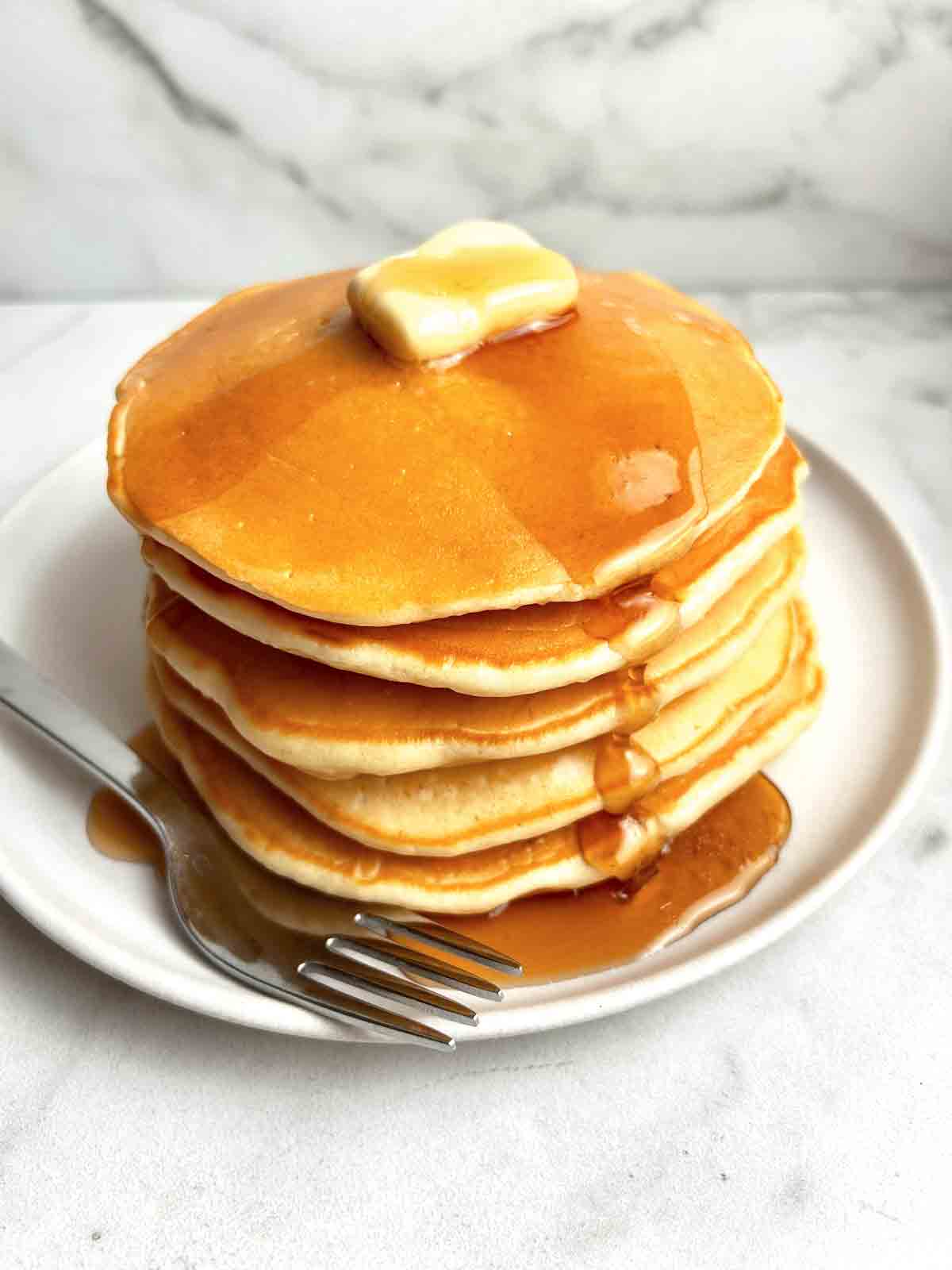 stack of pancakes with syrup pouring off of them.