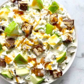 bowl of Snickers salad with caramel drizzled on top.