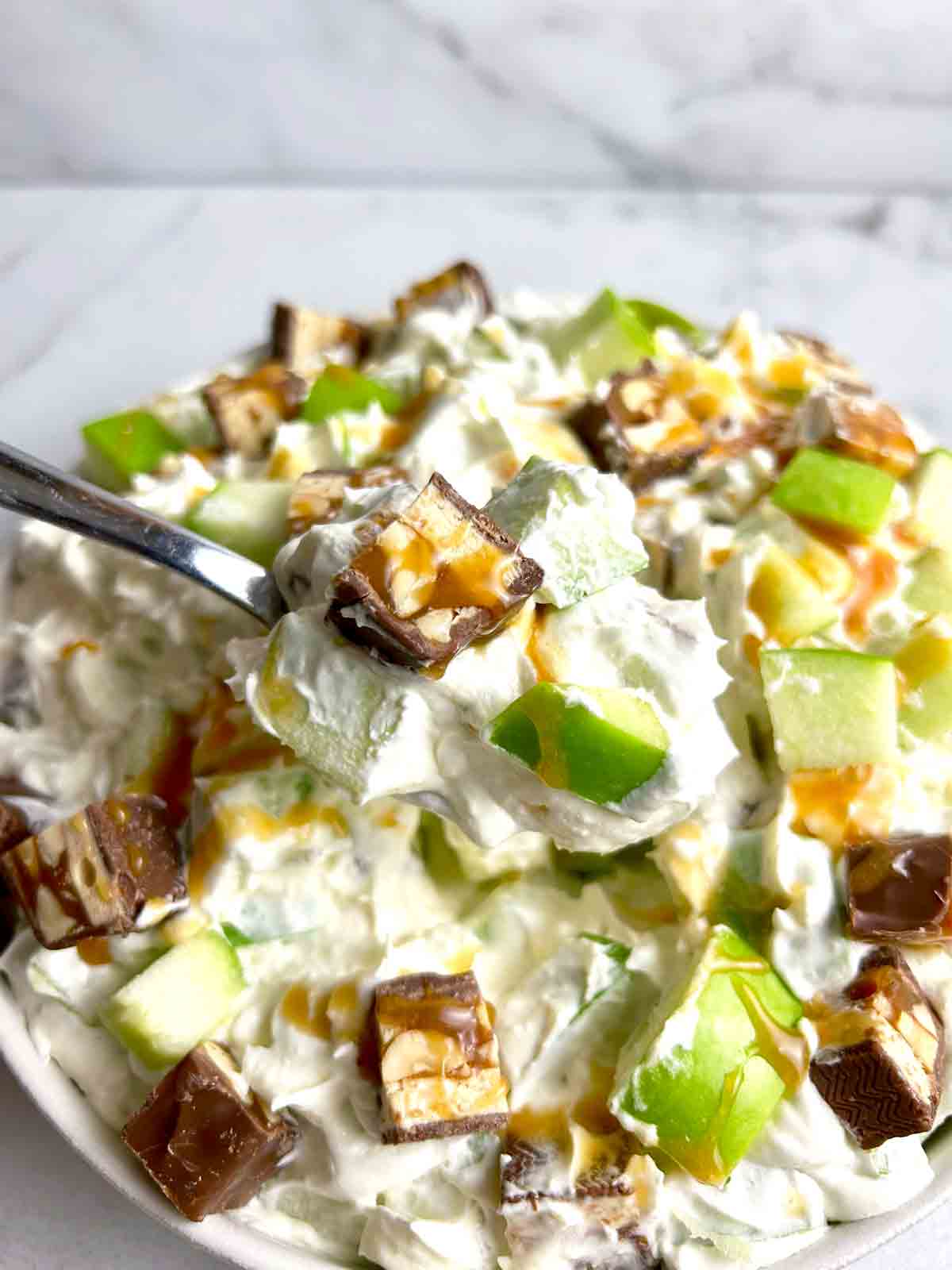 spoon lifting Snickers salad from bowl.
