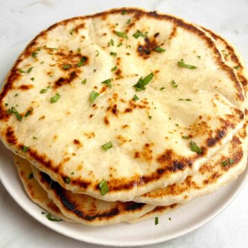 plate of sourdough naan with butter and parsley on top.