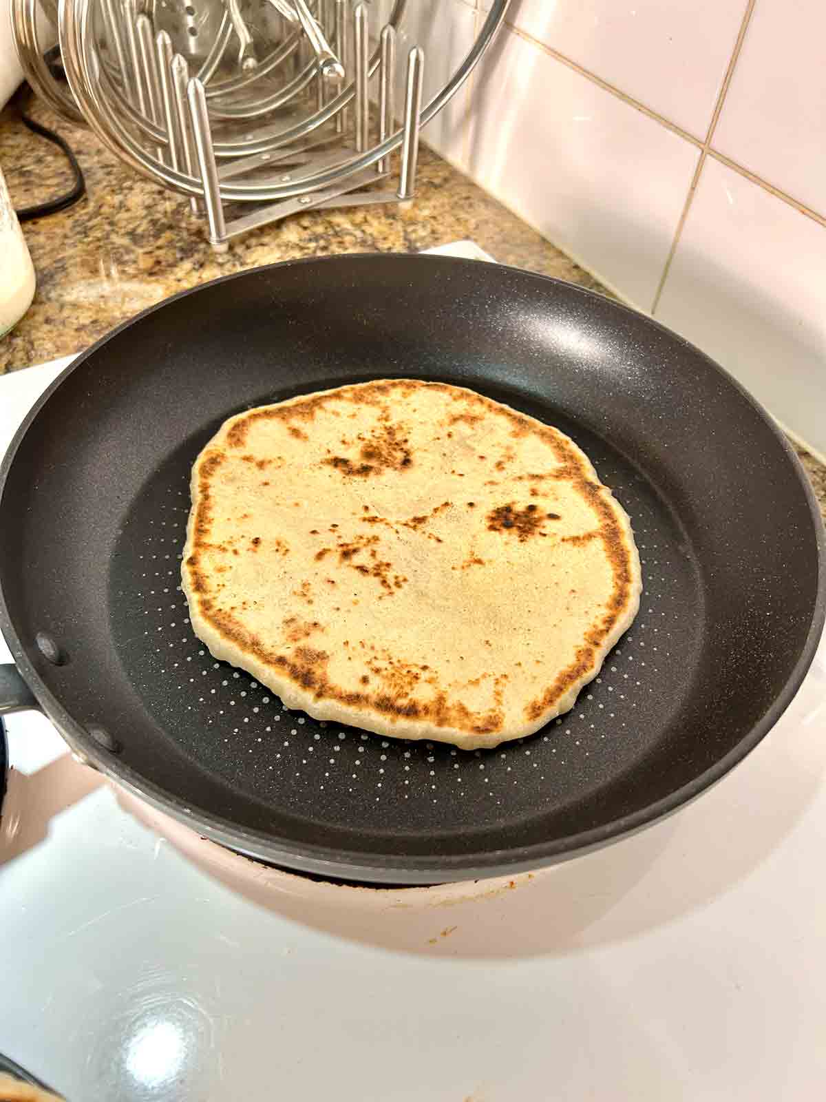 golden brown naan cooking in skillet.