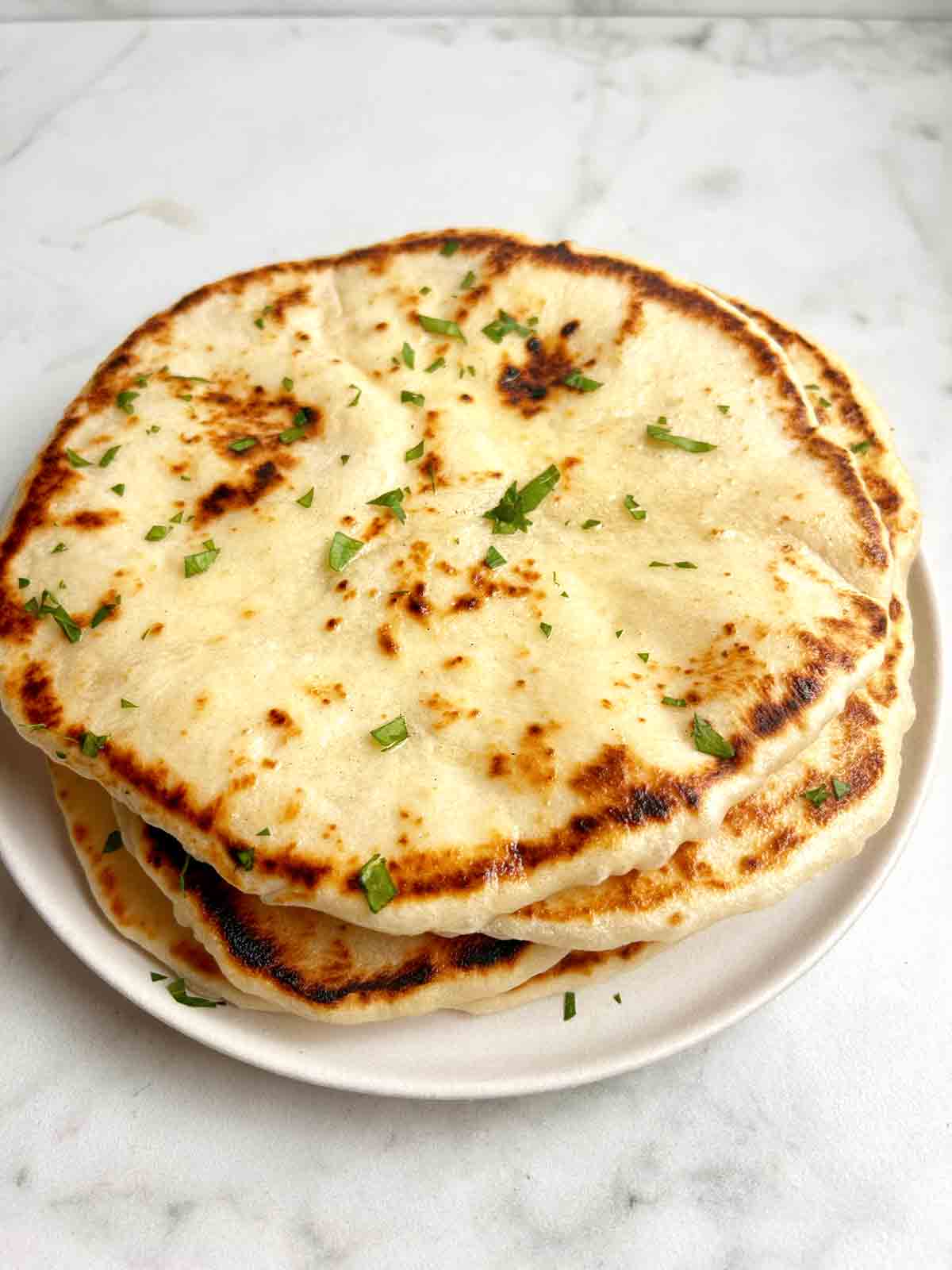 plate of sourdough naan with butter and parsley on top.