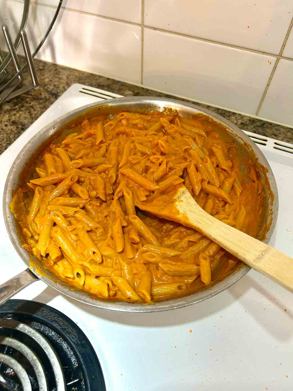 pasta mixed with sauce in skillet.