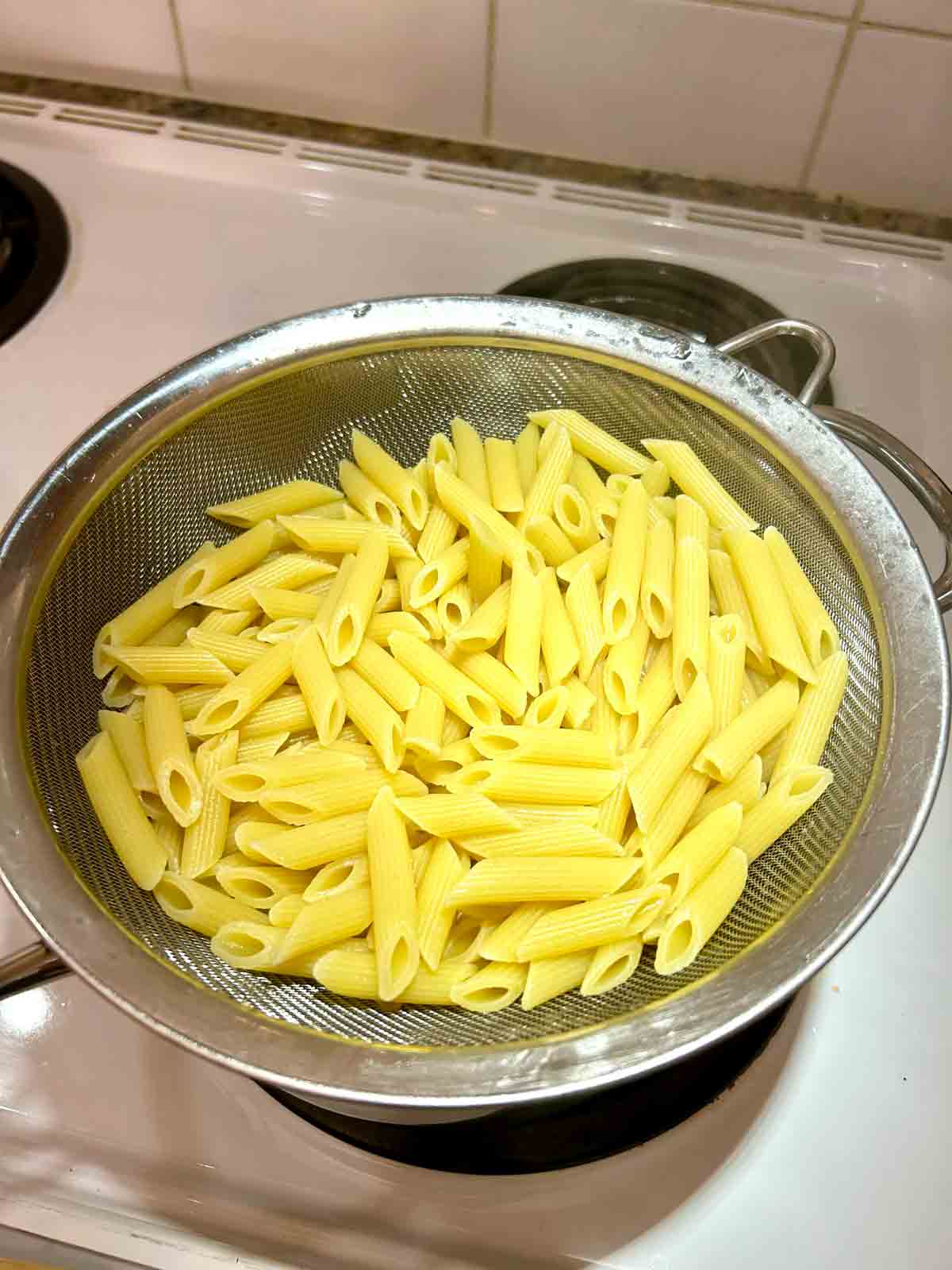 pasta cooked and draining in colander.