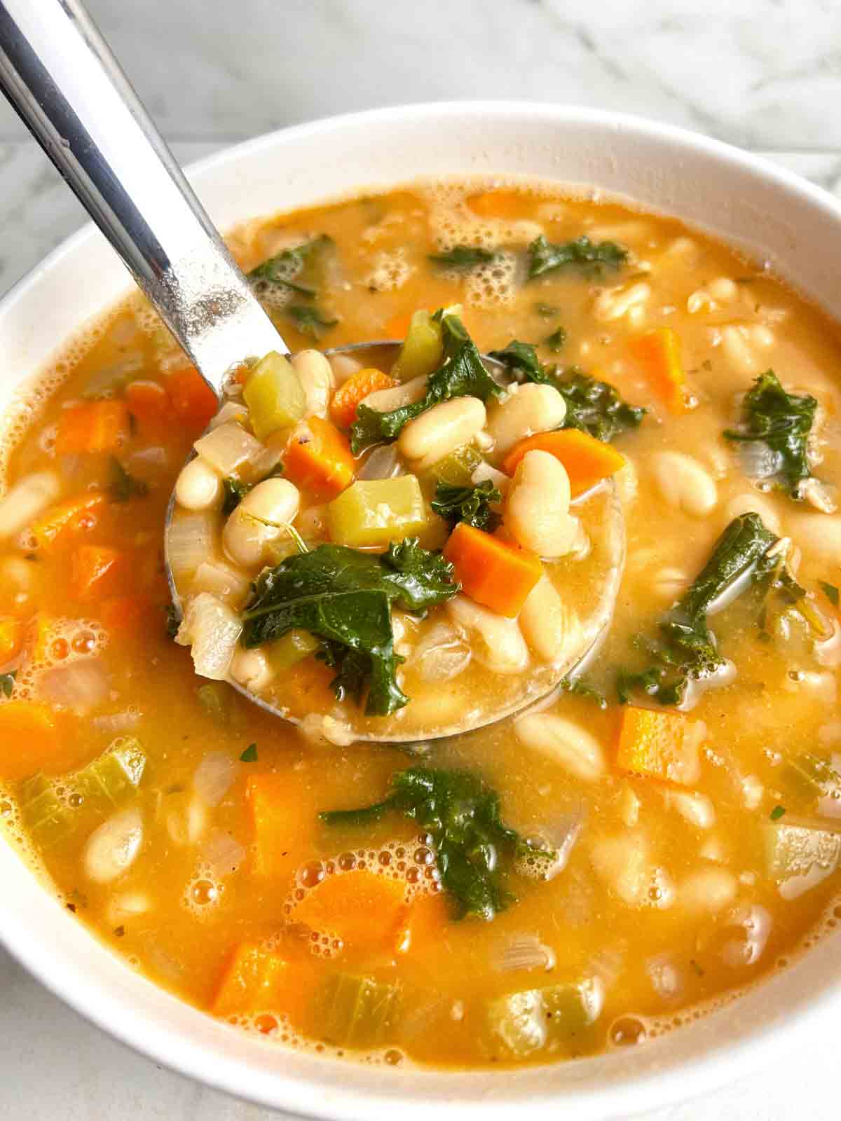 ladling white bean soup from large bowl.