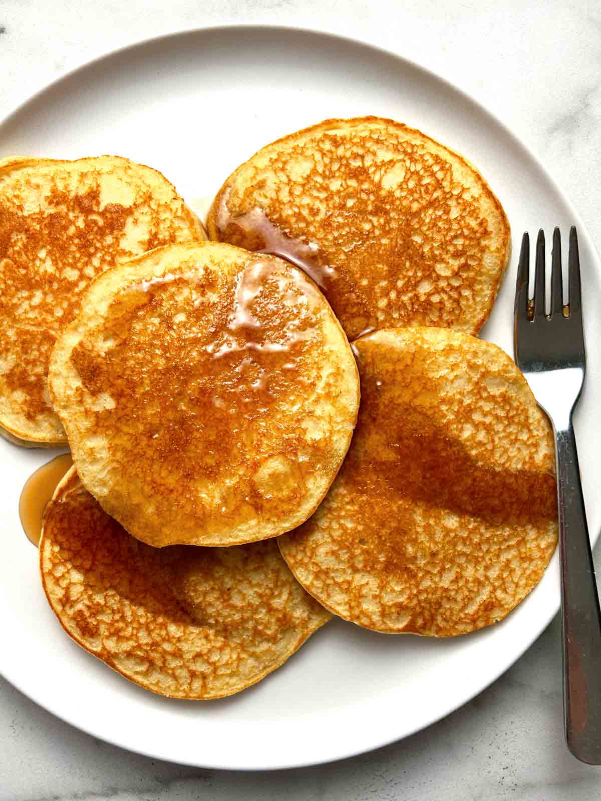 almond flour pancakes on plate; syrup poured over them.