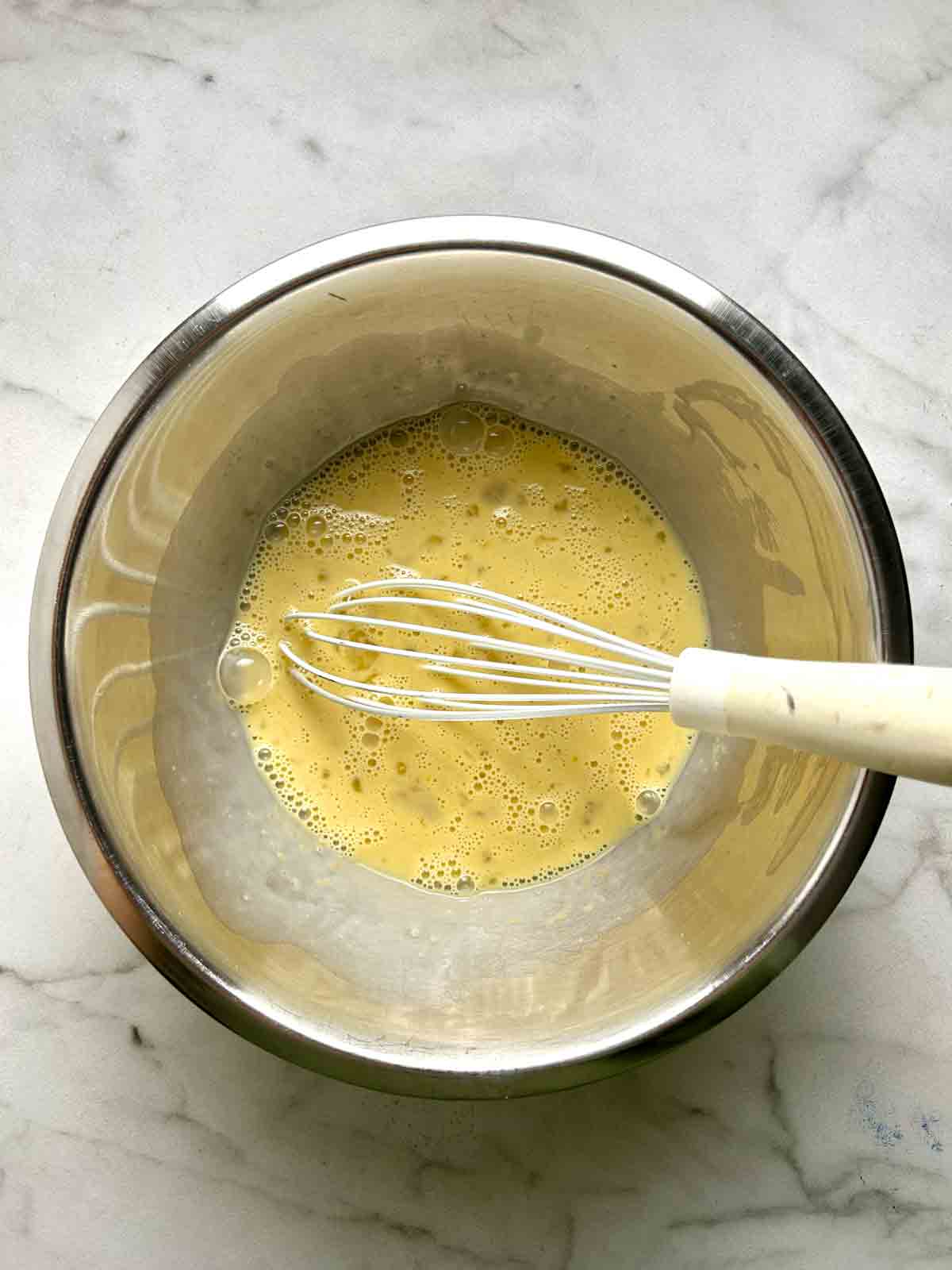 eggs whisked with milk in bowl.