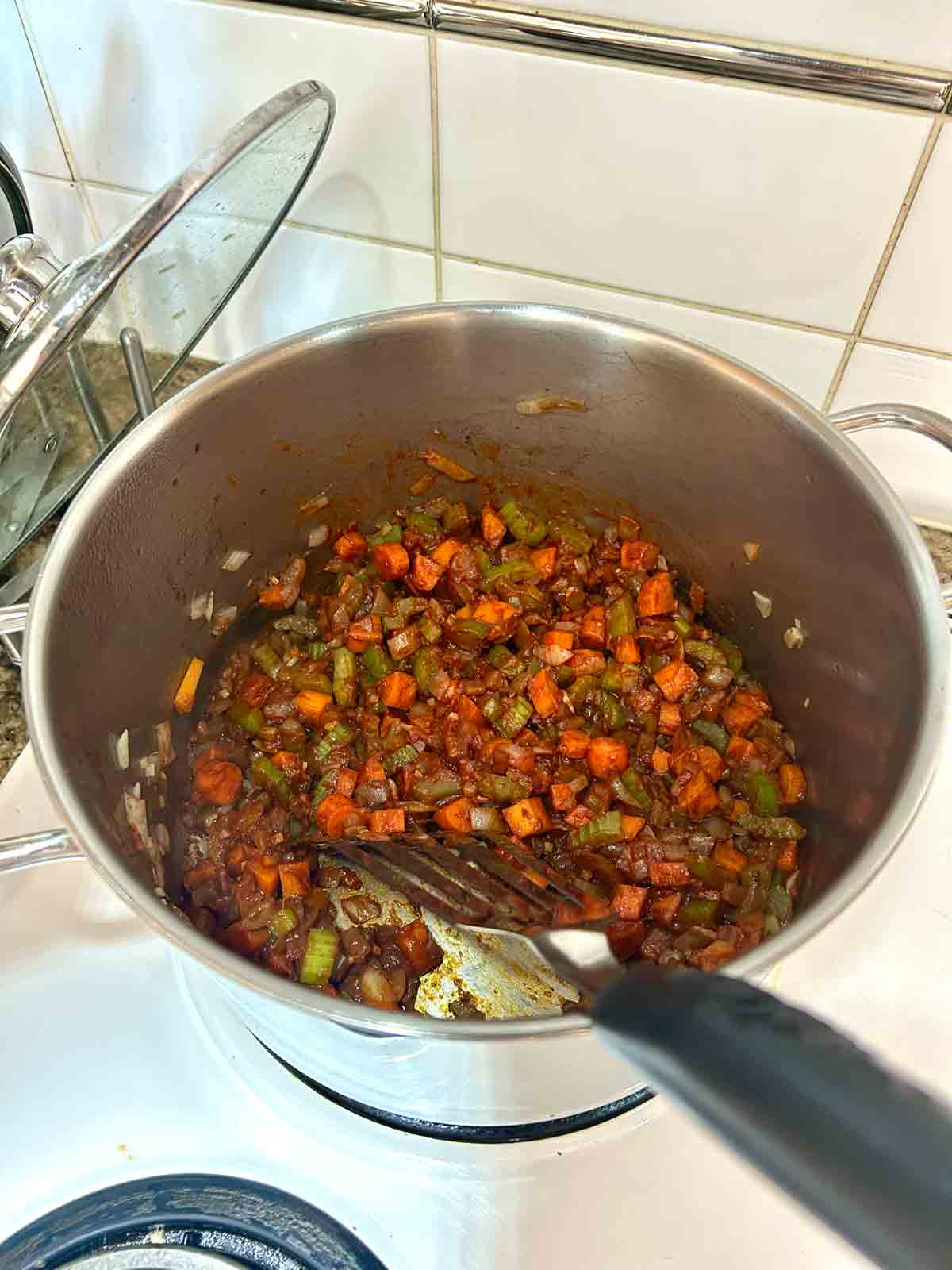 tomato paste stirred into vegetables in pot.