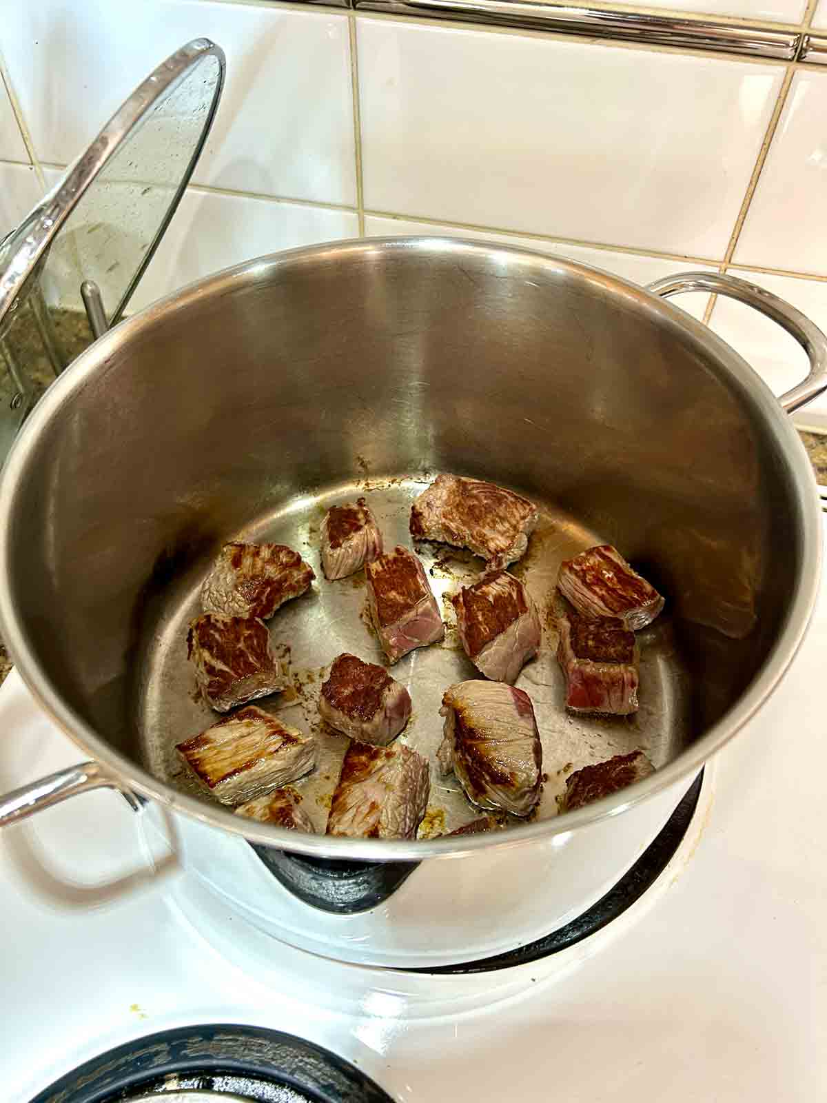 beef chunks being seared in pot.