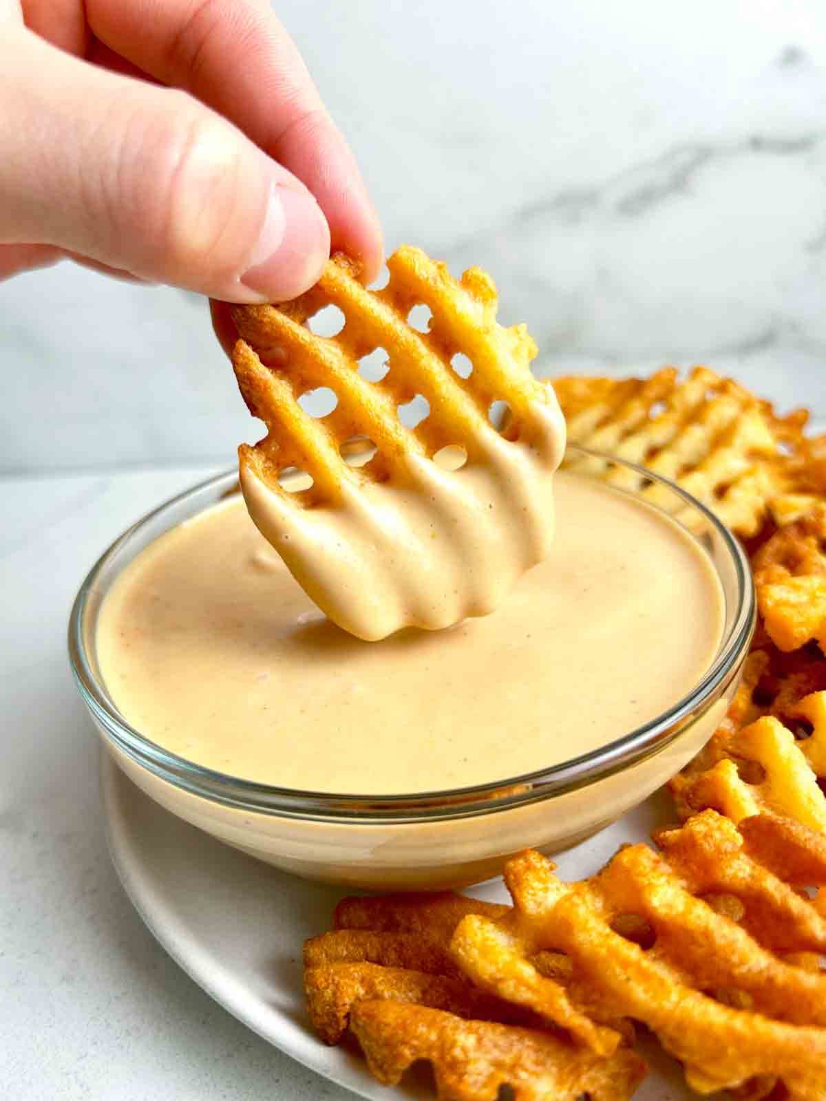 waffle fry being dipped into bowl of chick-fil-a sauce.
