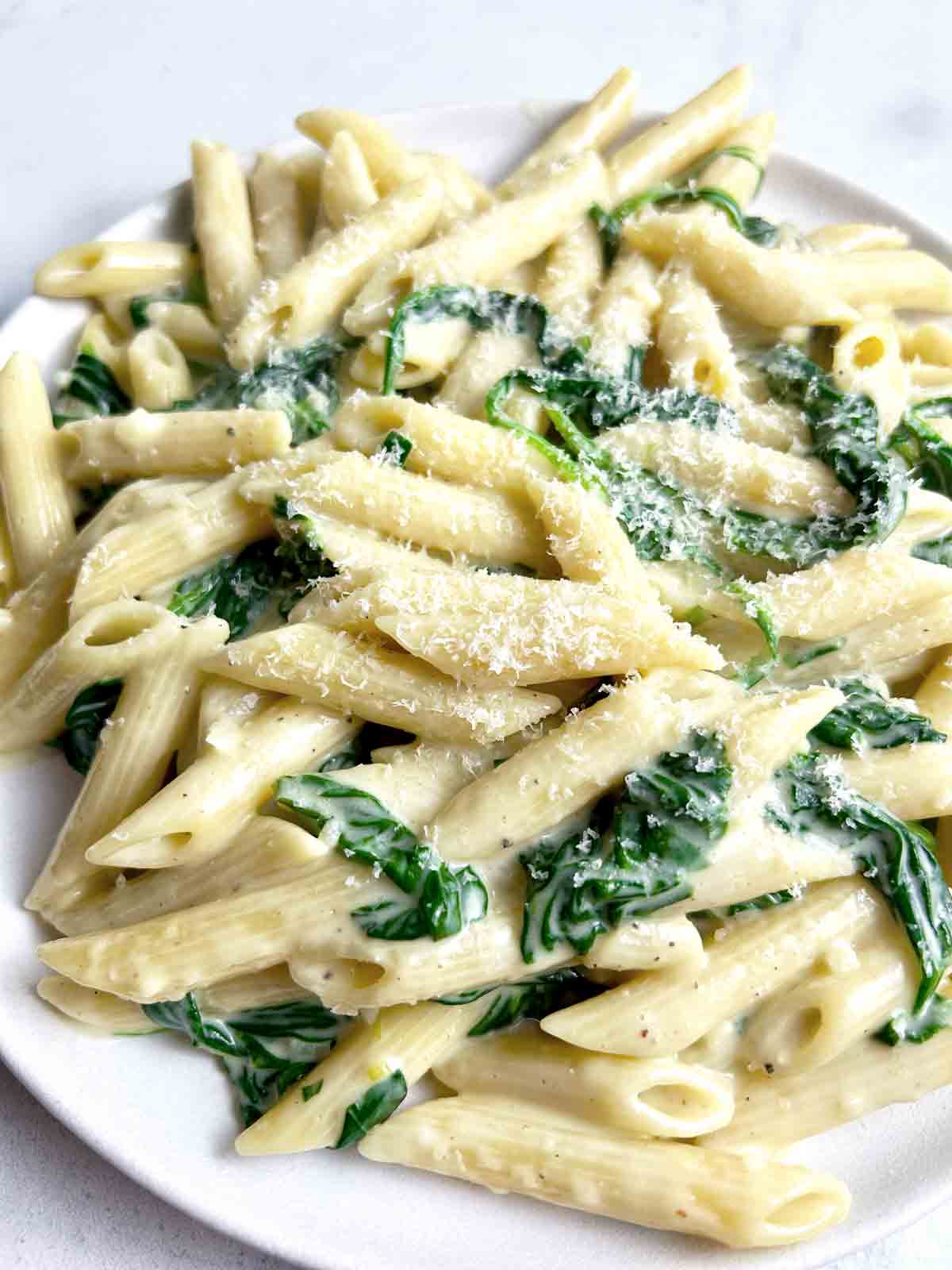 close up of creamy spinach pasta on plate.