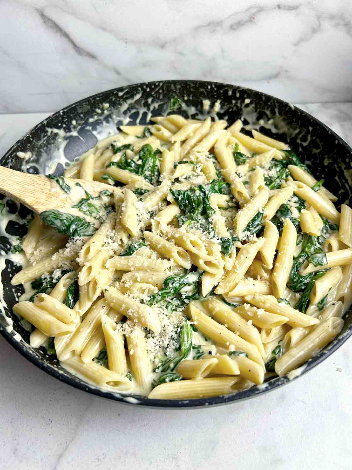 creamy spinach pasta in skillet.