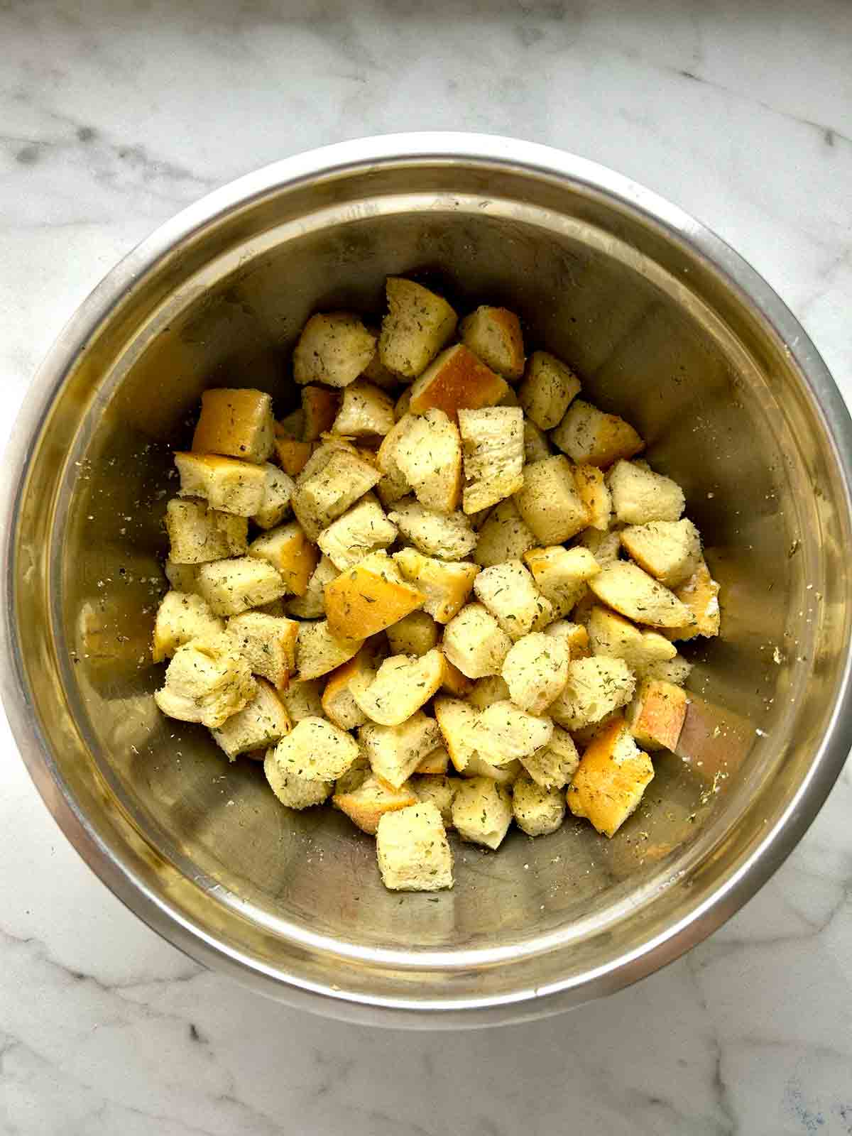 seasonings added to bowl of bread cubes.