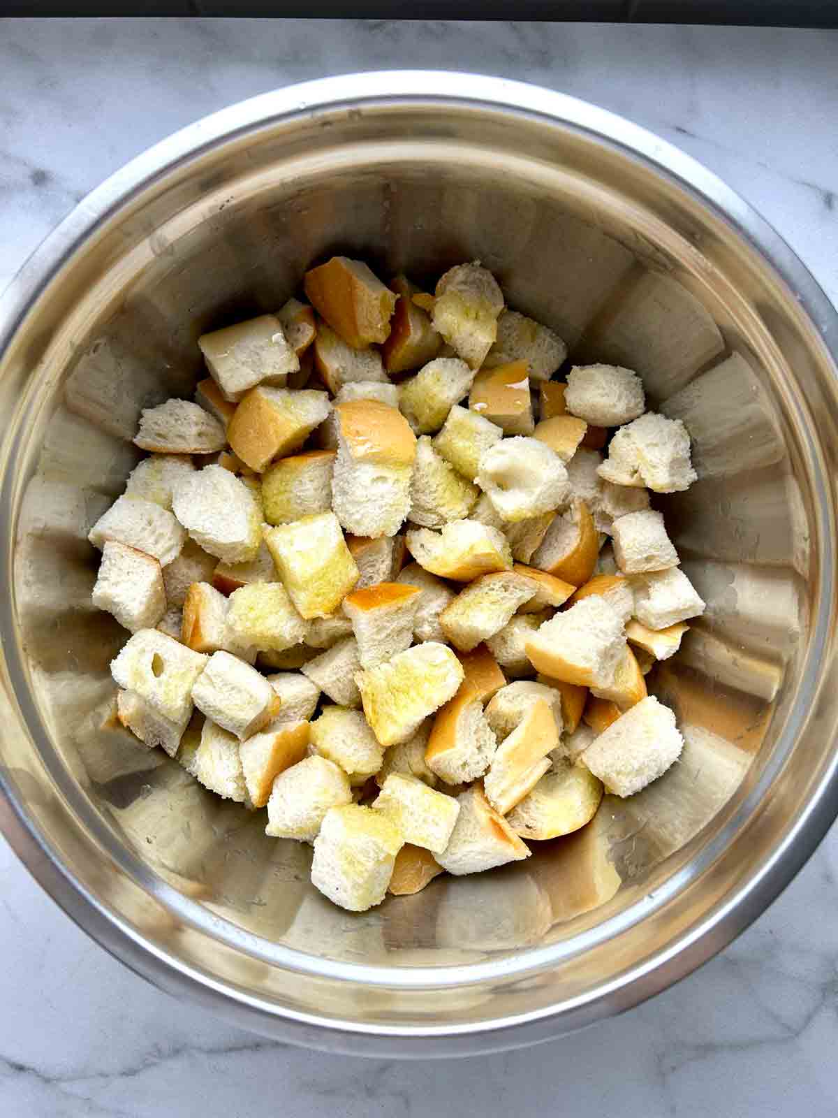 bread cubes tossed with oil in bowl.