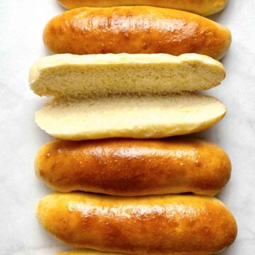 close up of hot dog buns with one cut in half and opened.